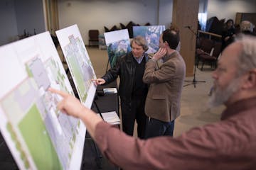 Steven Truax, left, and John Guerra discussed the plans on the display before the meeting began Wednesday night in the Minnehaha Academy chapel.