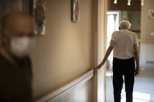 FILE - In this April 16, 2020, file photo, Richard Eberhardt walks along a corridor at a nursing home in Kaysesberg, France. Countries across Europe are struggling amid the coronavirus pandemic with the dilemma of leaving the elderly and others near death in enforced solitude or whether to allow some personal contact with relatives. At nursing homes, everything is done to keep out visitors who might be infected, and family members are almost always banned from coming to see their loved ones.