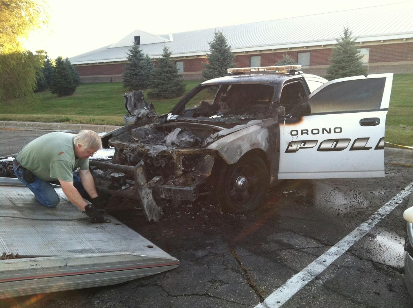 Officials prepare to tow away one of two Orono police squad cars that were destroyed by fire early Friday in the department parking lot. Authorities are looking at the possibility of arson.