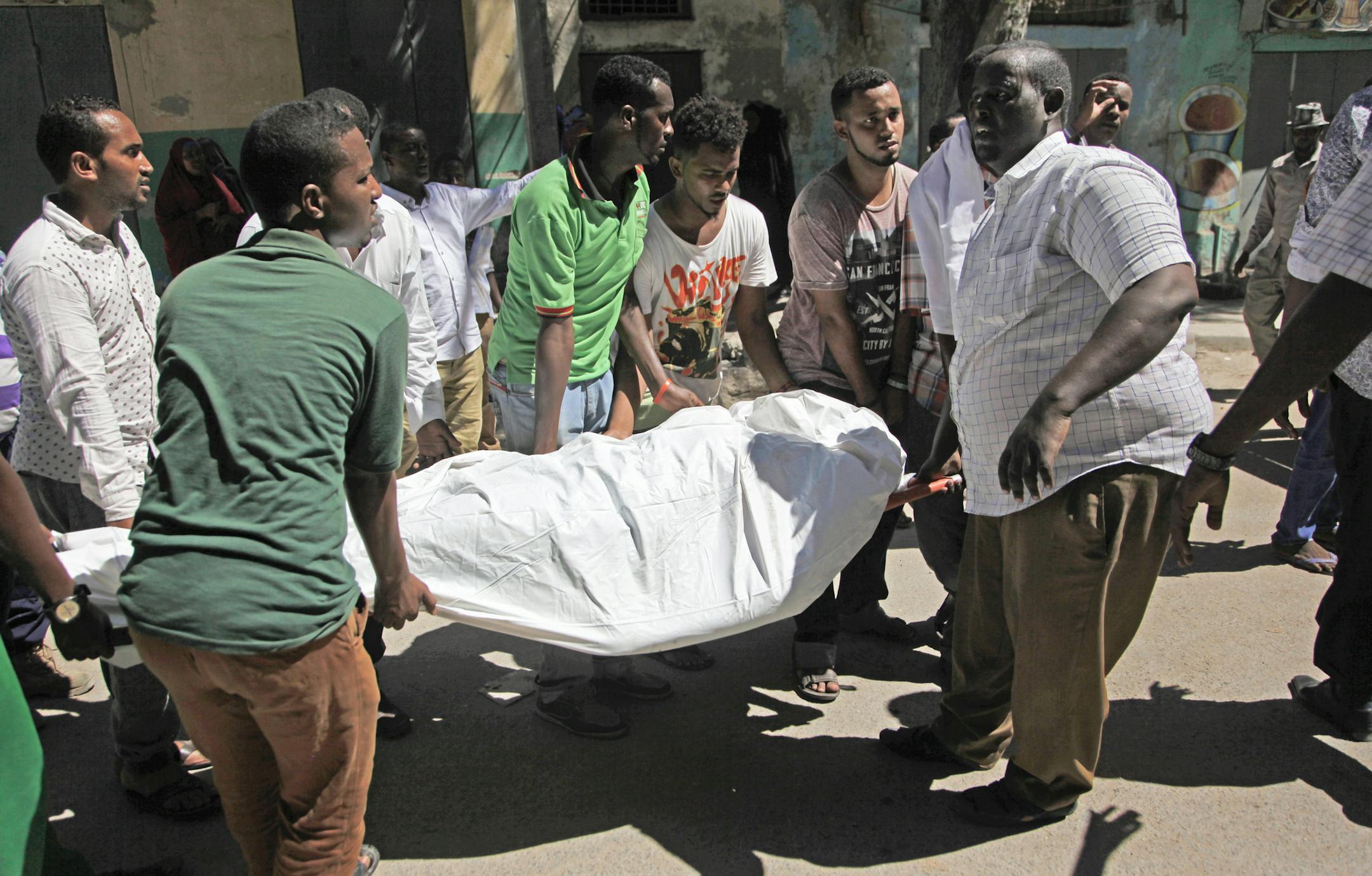 Somalis carry away a dead body from the scene of a car bomb attack in the capital Mogadishu, Somalia, Monday, April 11, 2016. A car bomb exploded outside a restaurant packed with lunchtime customers, killing at least five people according to witnesses in the capital's Hamarweyne district, close to the municipal government headquarters and a busy commercial area. (AP Photo/Farah Abdi Warsameh)