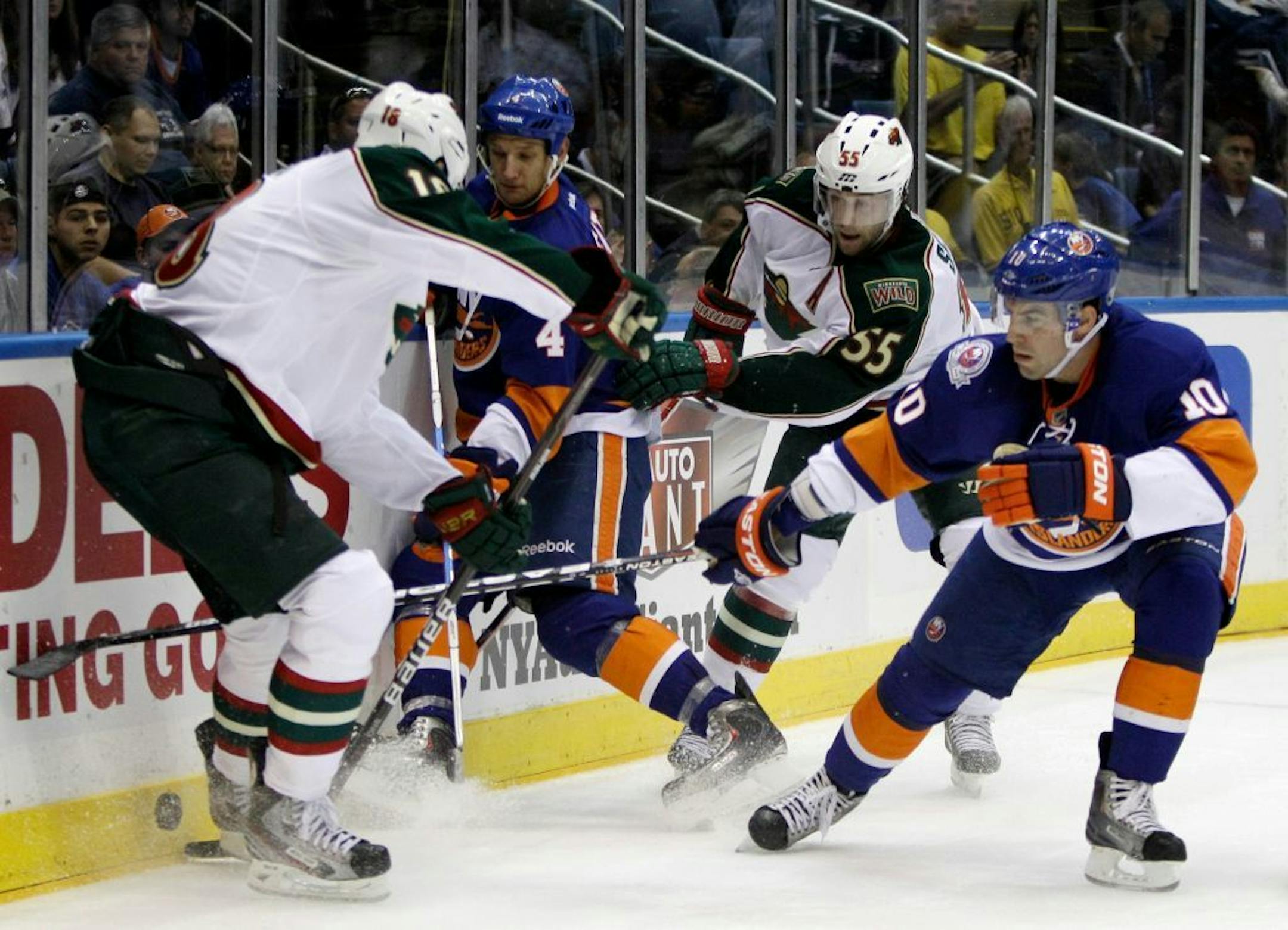Minnesota Wild's Devin Setoguchi (10), left, and defenseman Nick Schultz (55) fight for the puck with New York Islanders defenseman Mark Eaton (4) and defenseman Mike Mottau (10) behind the Islanders goal in the first period of their NHL hockey game at Nassau Coliseum in Uniondale, N.Y., Monday, Oct. 10, 2011.