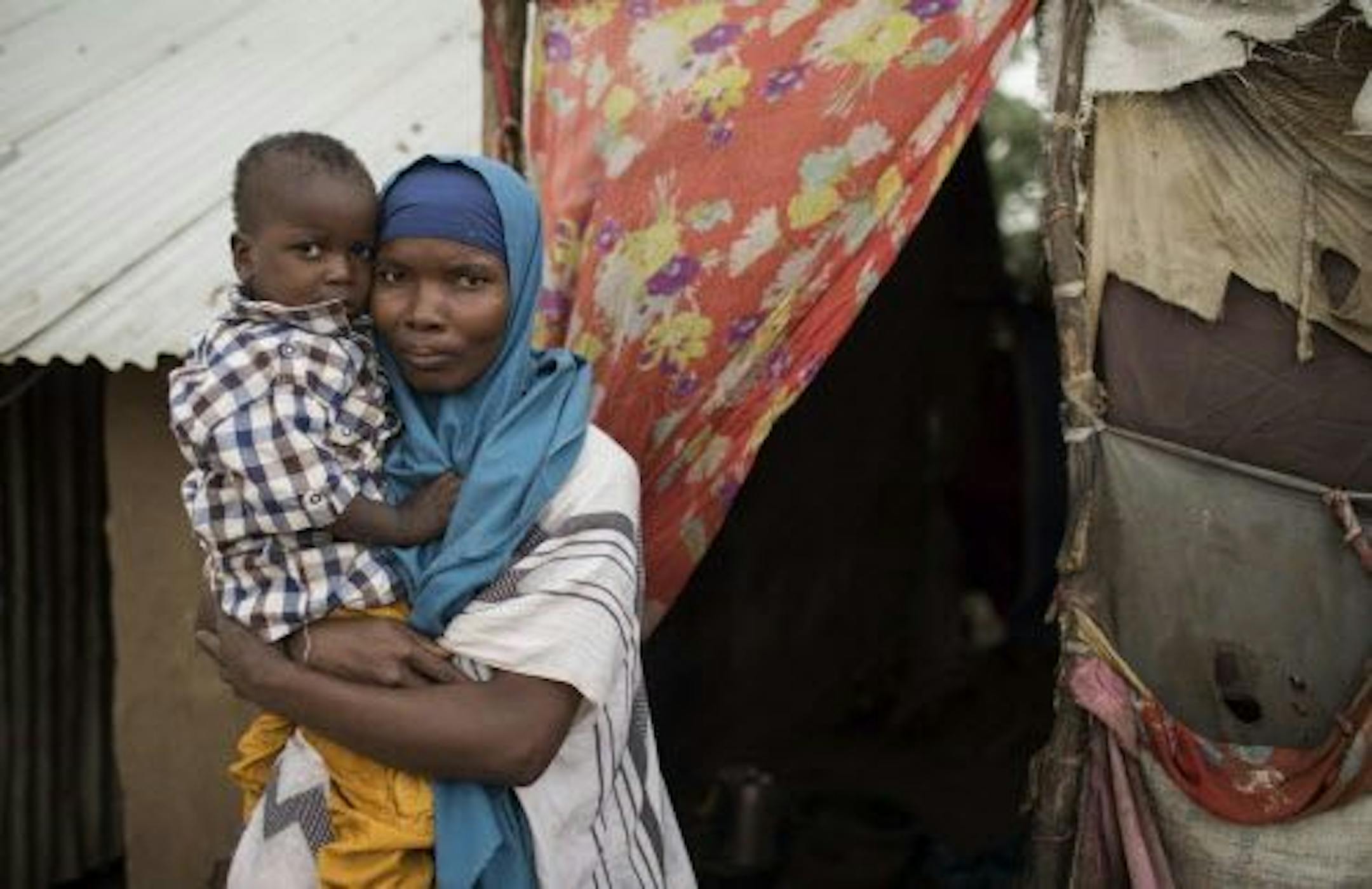 In this photo taken Monday, July 31, 2017, Somali refugee and mother of four Asho Manangara Ibrahim, 30, holds her one-year-old son Juuma Maday Jeylani, by the doorway of their home at Kakuma Refugee Camp in northern Kenya. For 10 years Ibrahim went through a rigorous process of interviews and screening and finally was cleared to travel to the United States, but now her hopes have been dashed after the U.S. Supreme Court on Tuesday, Sept. 12, 2017 allowed the Trump administration to maintain its