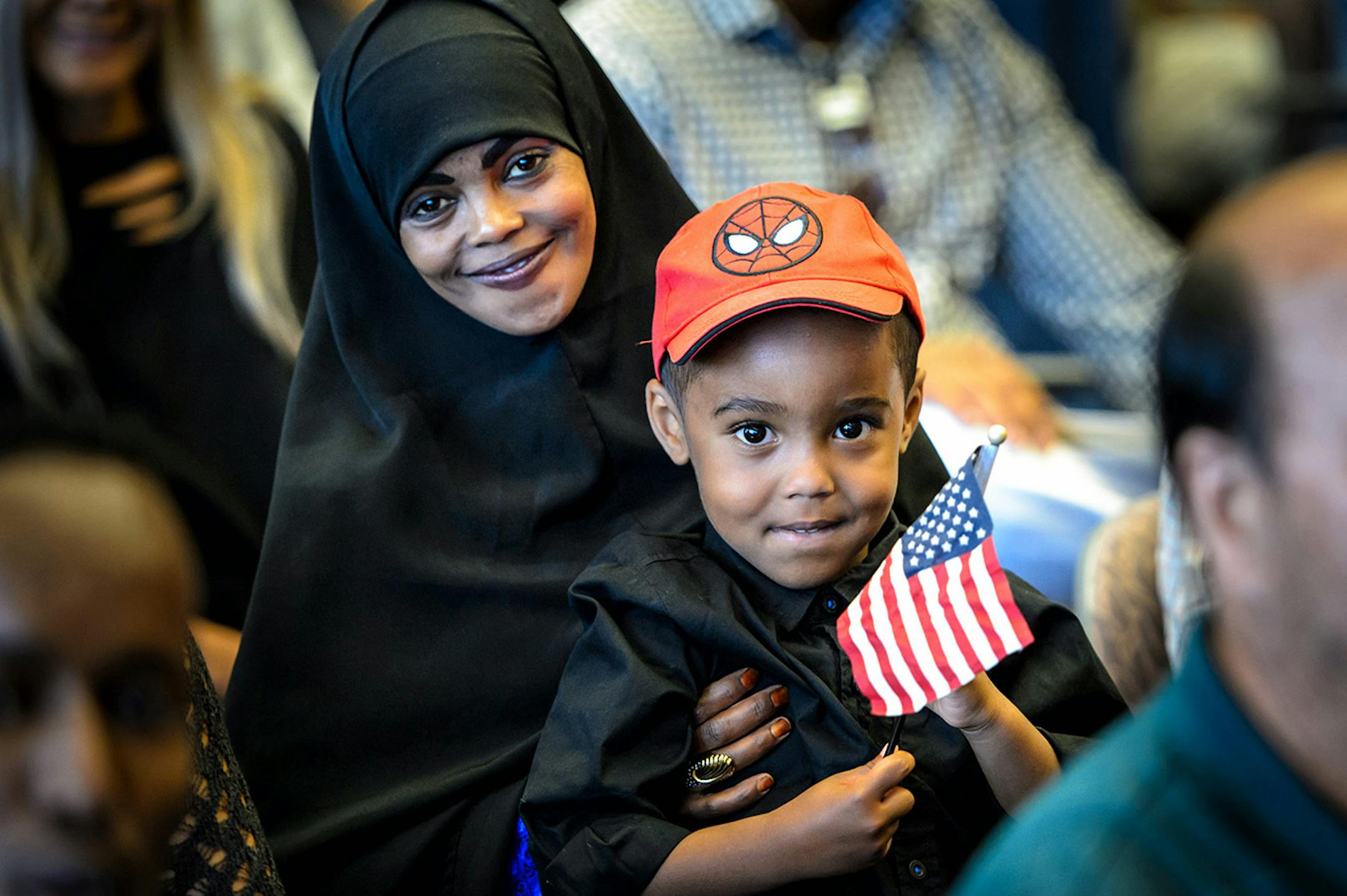 Ayuub Muse, 3, waved a flag as his mom Amina Yusuf, left, became a U.S. citizen.