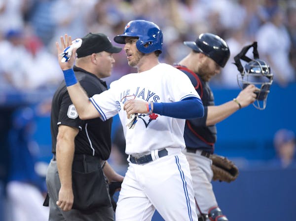 Toronto Blue Jays catcher J.P. Arencibia celebrates scoring as Minnesota Twins catcher Ryan Doumit reacts during the fourth inning of a baseball game 