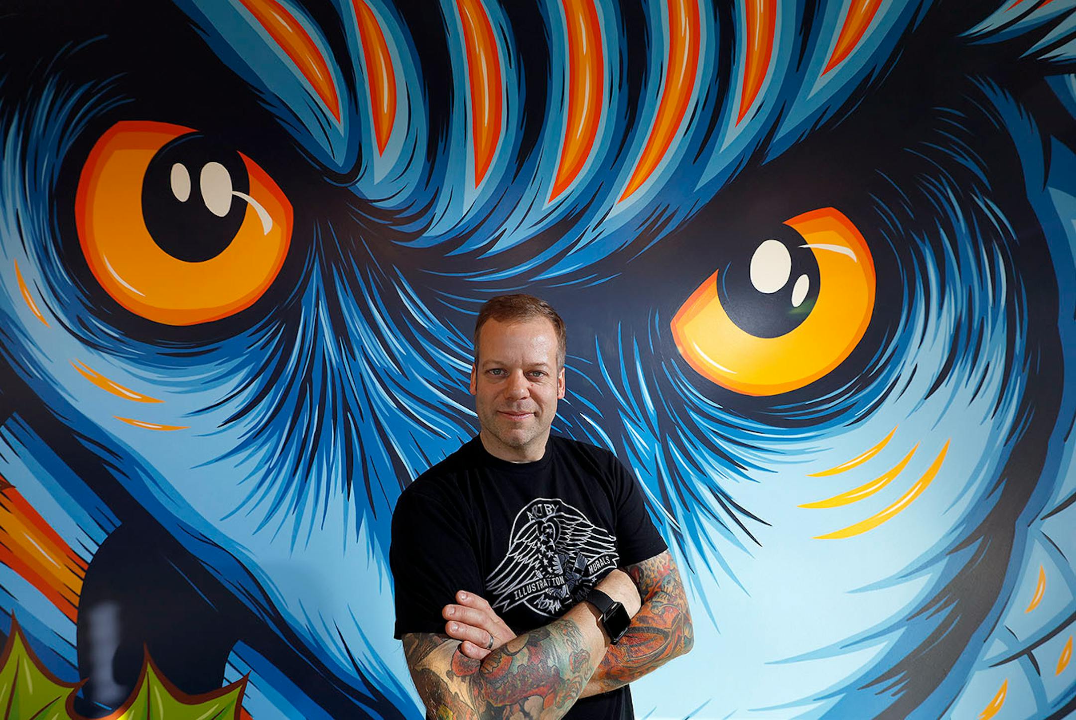 Graphic artist ,Adam Turman in front of his owl mural, which is located at the A-Mill Artist Lofts in Minneapolis.