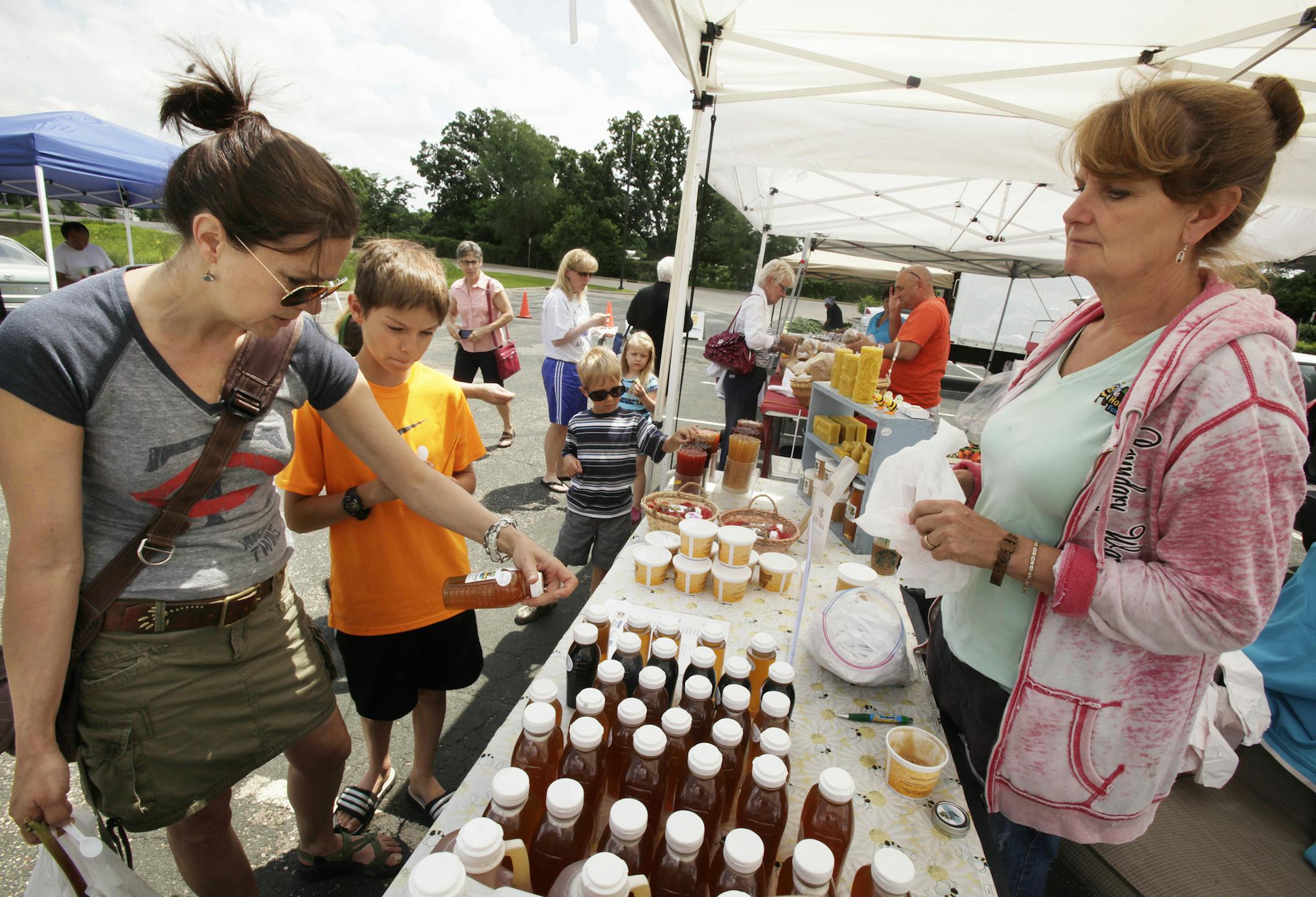 Wendy Barnum and her son Ian Barnum of Lakeville look at the honey that Arlene Hill of Aspen Ridge Honey Farm had on display at the farmers market in Rosemount, MN. June 18, 2013. ] JOELKOYAMA‚Ä¢joel koyama@startribune.com The farmers market in Rosemount, MN. June 18, 2013. ] JOELKOYAMA‚Ä¢joel koyama@startribune.comAfter a late spring and a rainy and cold start to the farmers' market season, we check in to see how the bad luck is affecting south metro markets, a