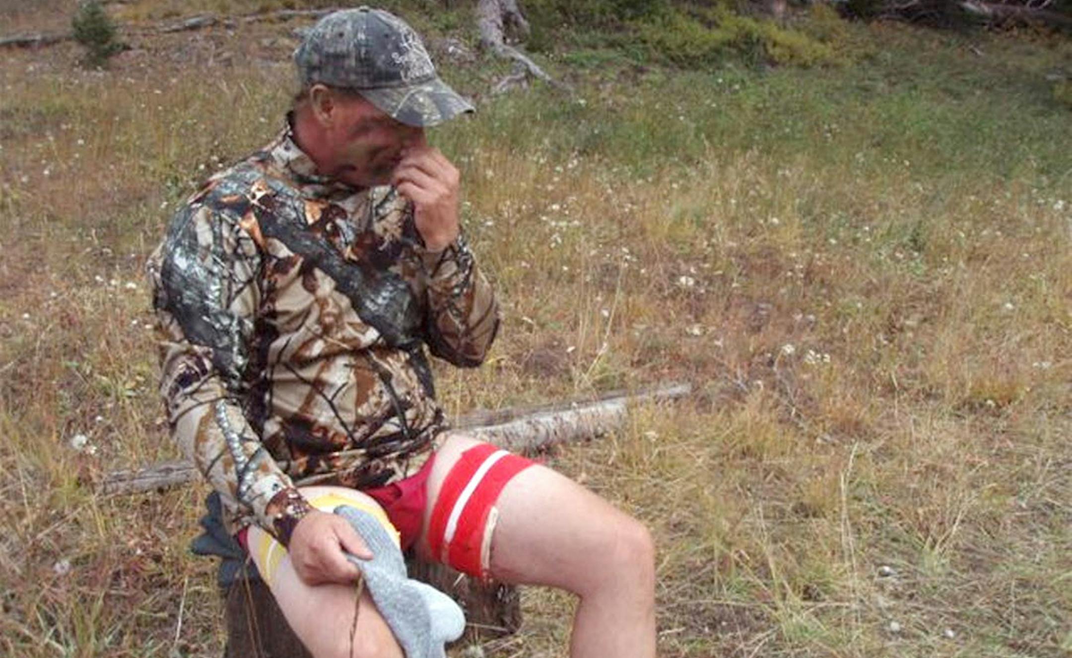 Kim Wunderlich sitting on a stump with his wounds bandaged with a horse wrap.