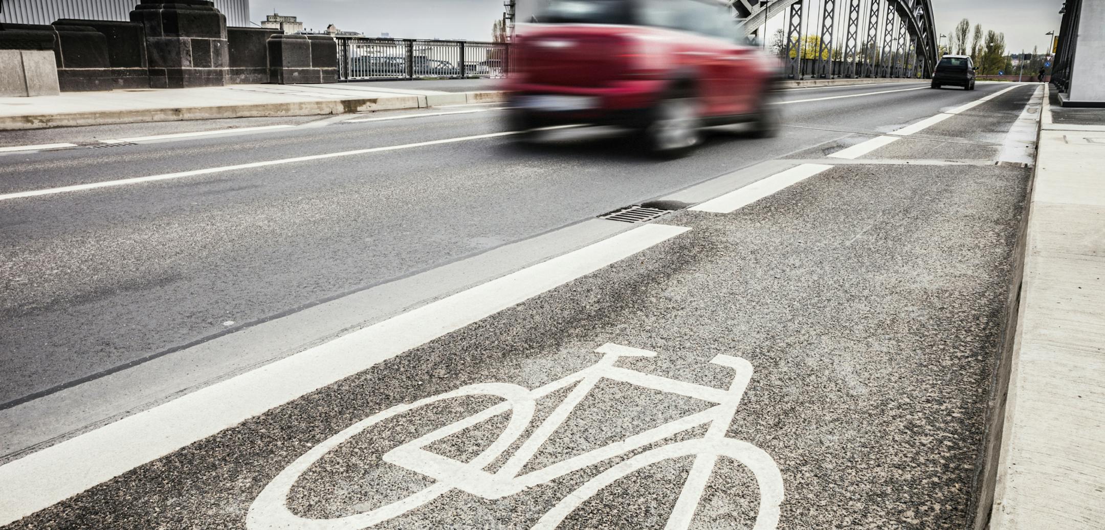 Empty bike lane with cars whizzing past.