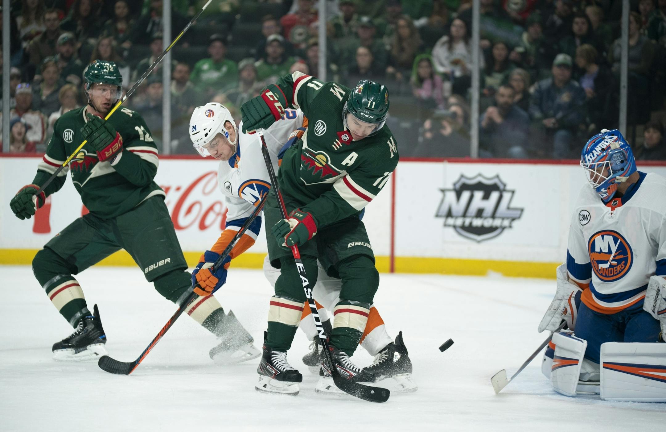 Minnesota Wild left wing Zach Parise (11) deflected a first period shot in front of New York Islanders goaltender Thomas Greiss (1) as he was defended by New York Islanders defenseman Scott Mayfield (24).