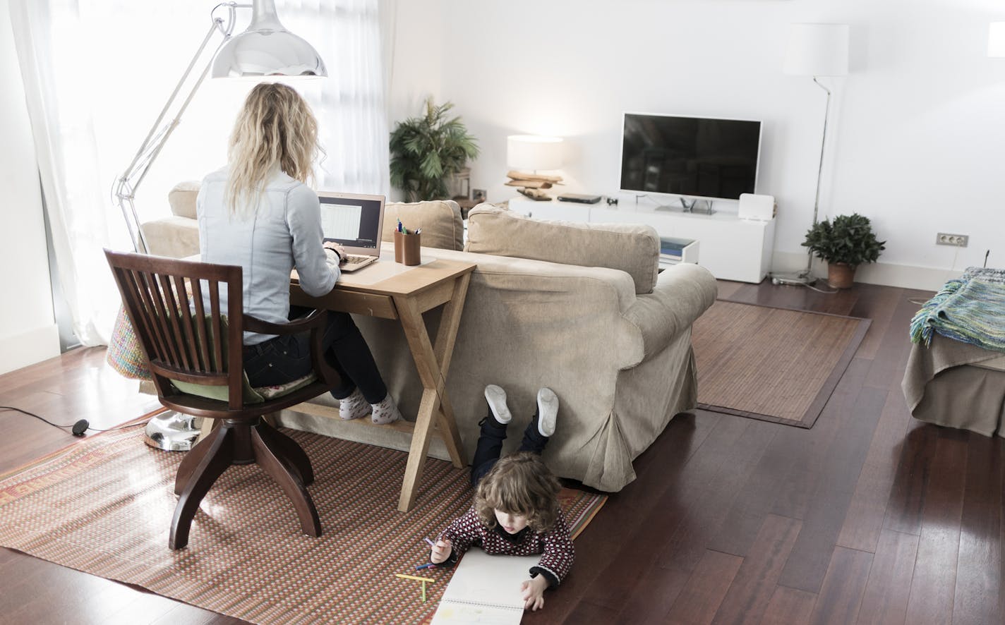 Mother working while child is drawing at home