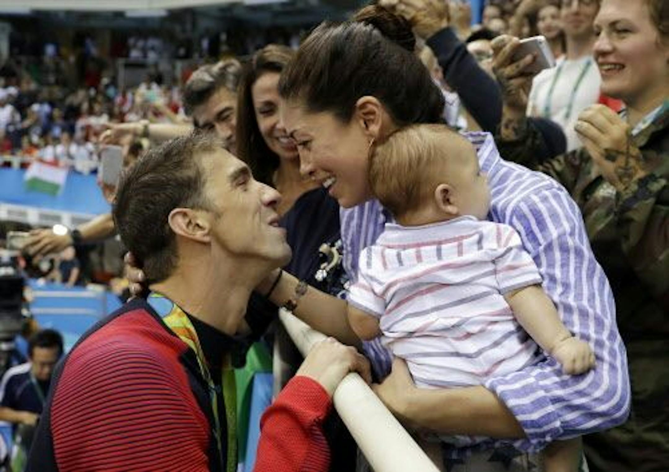 FILE - In this Aug. 9, 2016, file photo, United States' swimmer Michael Phelps celebrates winning his gold medal in the men's 200-meter butterfly with his fiance Nicole Johnson and baby Boomer during the swimming competitions at the 2016 Summer Olympics, in Rio de Janeiro, Brazil. The Arizona Republic reported Oct. 26, 2016, that Phelps and Johnson secretly married on June 13, 2016.