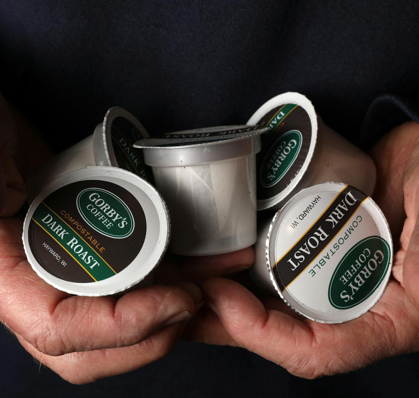 George Gorbatenko held out a pile of fully compostable coffee pods he designed. ] ANTHONY SOUFFLE &#xef; anthony.souffle@startribune.com George Gorbatenko, creator of a machine for coffee houses to turn their beans into pods that can be used in Keurig coffeemakers and similar devices, and his business partner Peter Middlecamp, roastmaster at Black Sheep Coffee Cafe, stood for a portrait Thursday, March 23, 2016 at their workshop in North St. Paul, Minn.