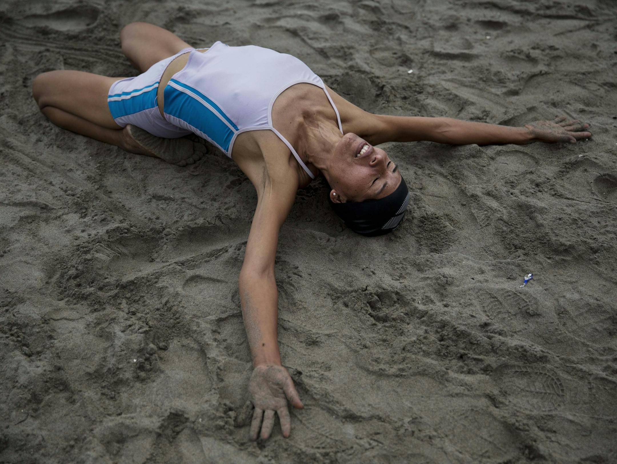 In this May 15, 2015 photo, Juana Coripuna stretches and meditates on Fishermen's Beach in Lima, Peru. Juana, 44, said she started going to the beach six years ago, and that thanks to meditation and swimming, she's improved both physically and mentally. (AP Photo/Rodrigo Abd)