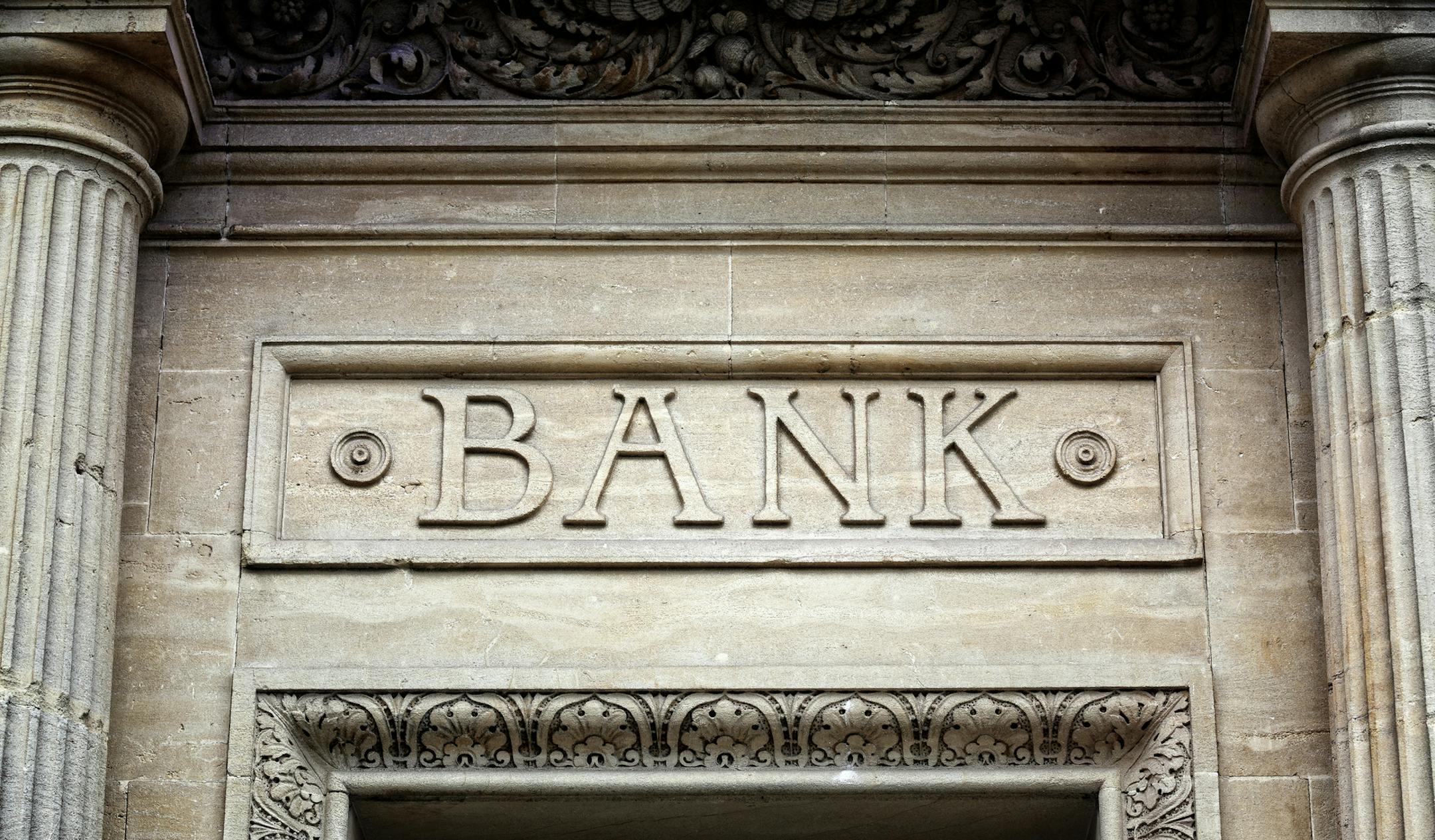 Old bank sign engraved in stone or concrete above the door of financial building concept for finance and business