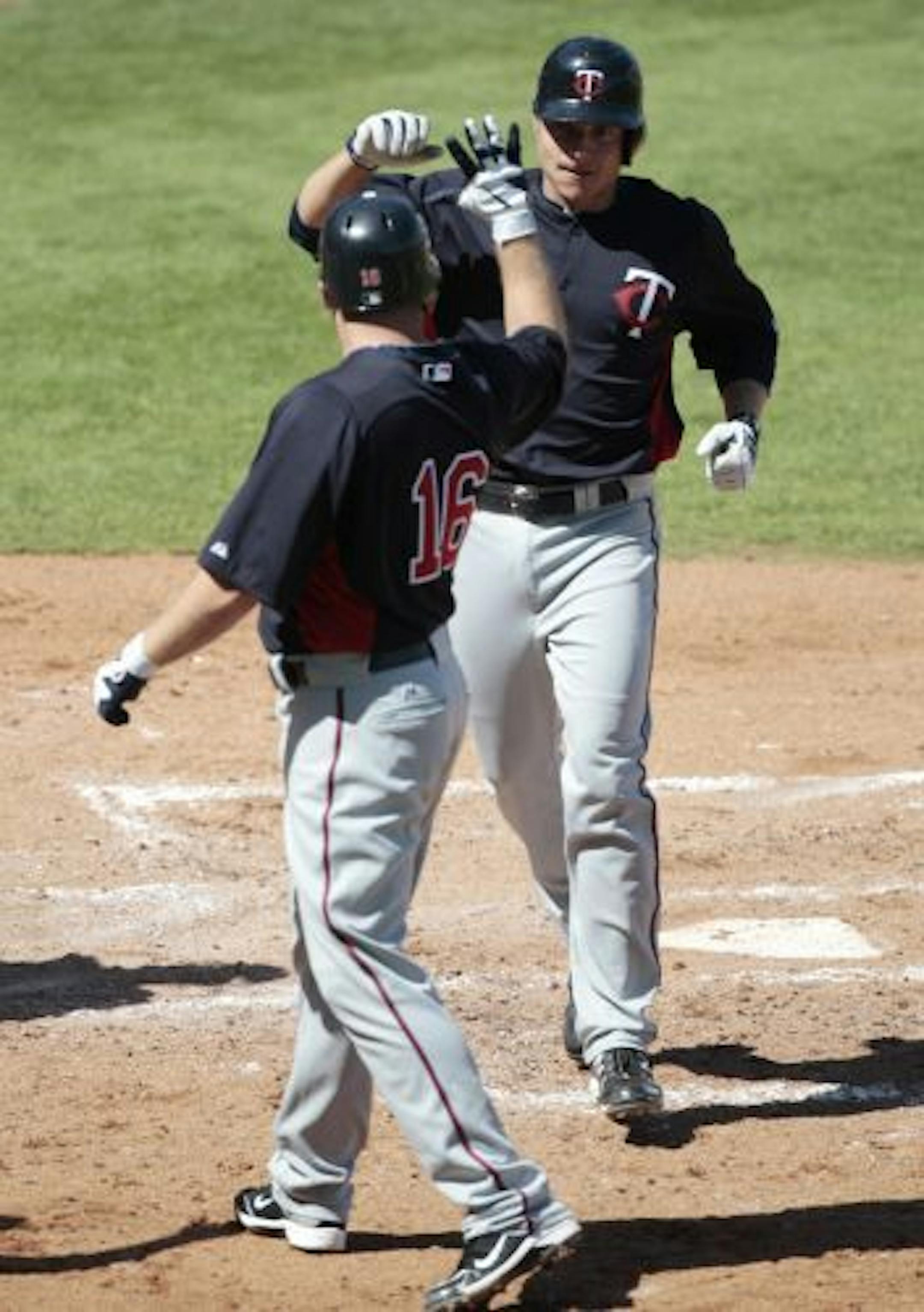 Minnesota Twins Luke Hughes, rear, is congratulated by teammate Jason Kubel in the third inning after Hughes batted in Kubel with a two run homer against the Boston Red Sox during their Grapefruit League spring training season baseball game at City of Palms Stadium in Fort Myers, Fla., Monday, Feb. 28, 2011.