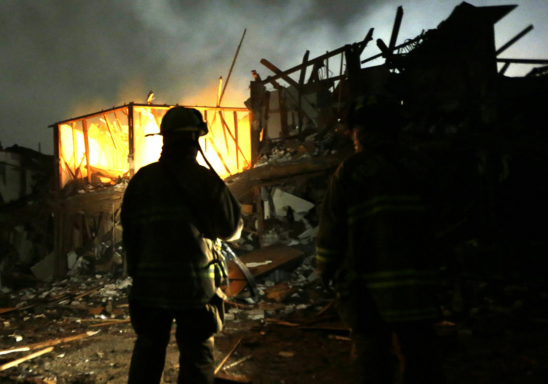 FILE - In this April 18, 2013, file photo, firefighters use flashlights to search a destroyed apartment complex near the West Fertilizer Co. plant that exploded in West, Texas. The Texas company that operated the fertilizer plant where a thunderous explosion in April killed 15 people is facing $118,300 in fines for two dozen serious safety violations, including a failure to have an emergency response plan, federal officials said Thursday, Oct. 10, 2013. (AP Photo/LM Otero, File) ORG XMIT: TXBS20
