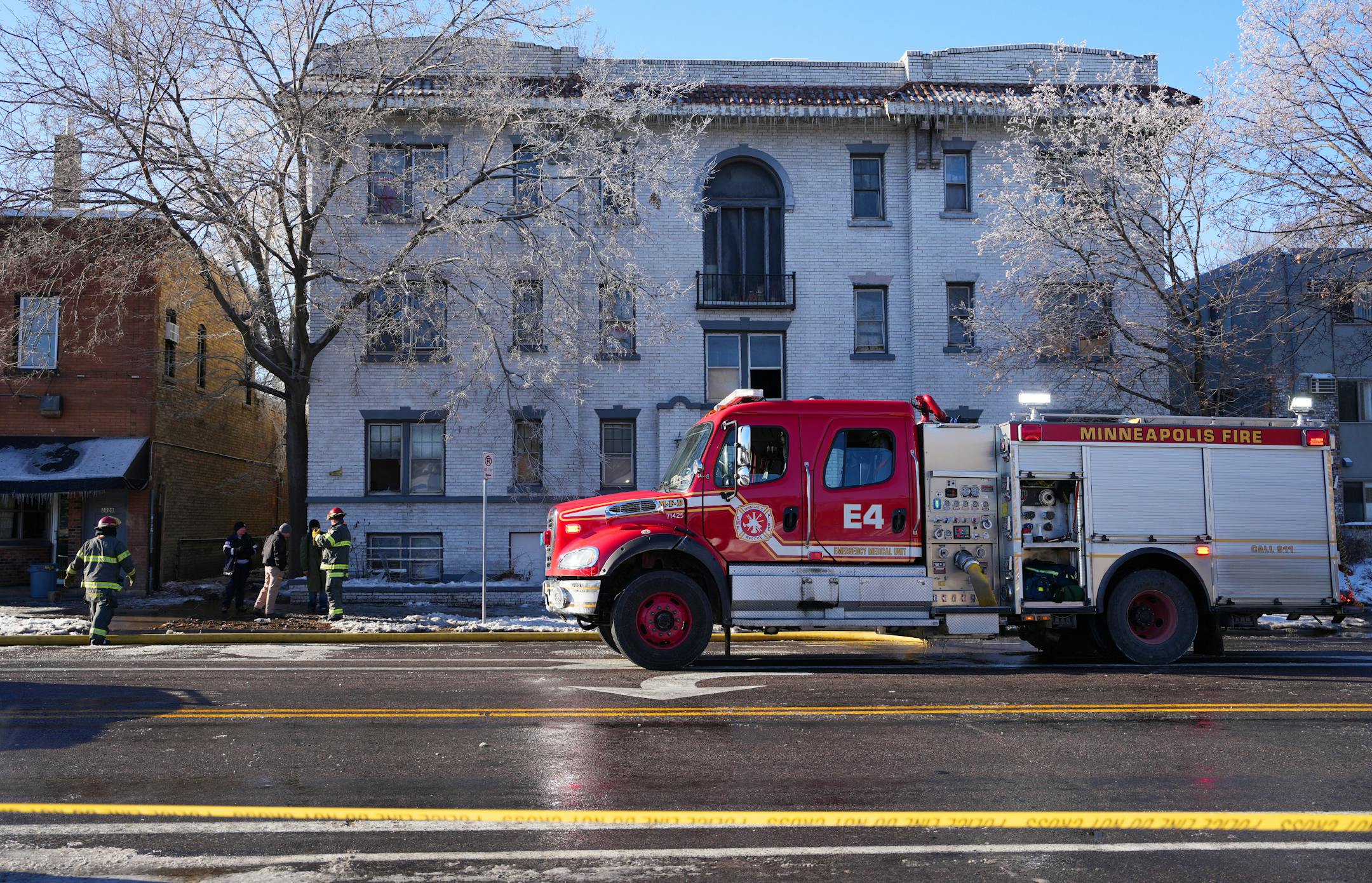A member of the State Fire Marshal's office and Minneapolis fire fighters talk with an individual outside the scene of a building fire Saturday, Dec. 3, 2022 in the 2300 block of Lyndale Avenue South in Minneapolis.