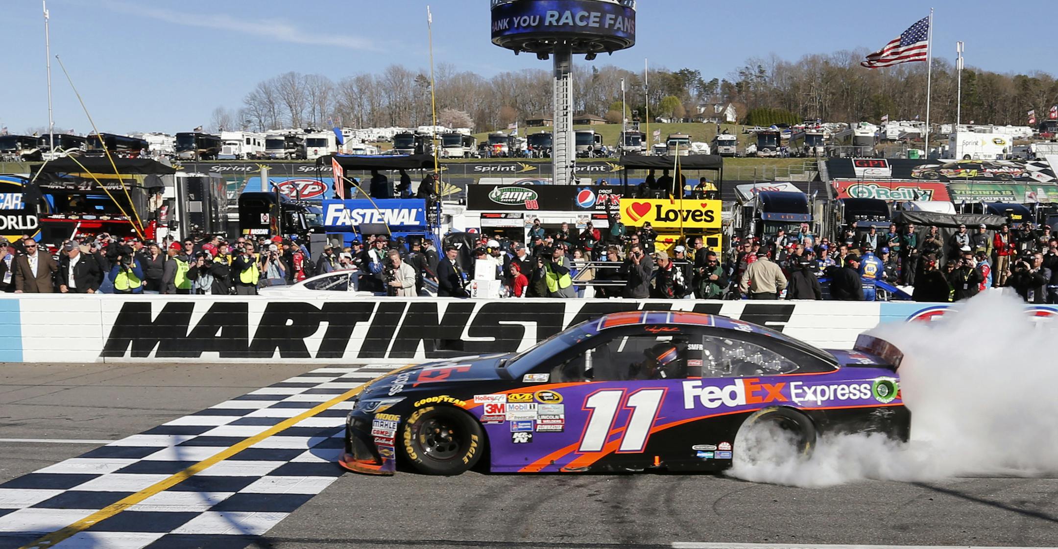 Denny Hamlin does a burnout after winning the NASCAR Sprint Cup Series auto race at Martinsville Speedway in Martinsville, Va., Sunday, March 29, 2015. (AP Photo/Steve Helber)