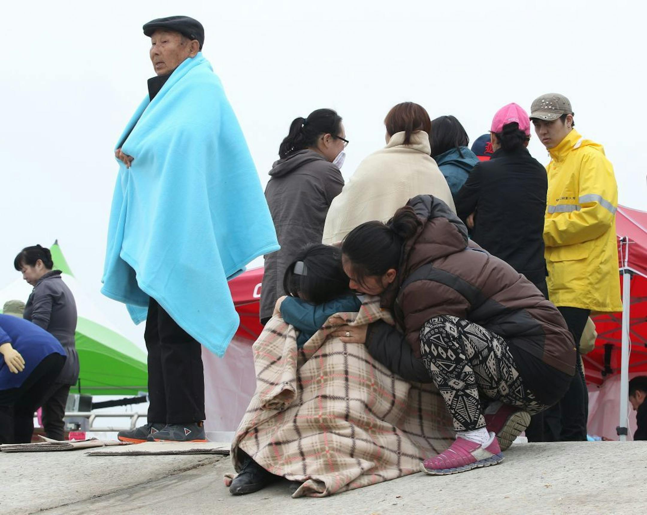 A relative of a passenger aboard the sunken ferry Sewol in the water off the southern coast is encouraged by her family members as they waiting for their missing loved ones at a port in Jindo, south of Seoul, South Korea, Saturday, April 19, 2014. Rescuers scrambled to find hundreds of ferry passengers still missing Friday and feared dead, as fresh questions emerged about whether quicker action by the captain of the doomed ship could have saved lives.