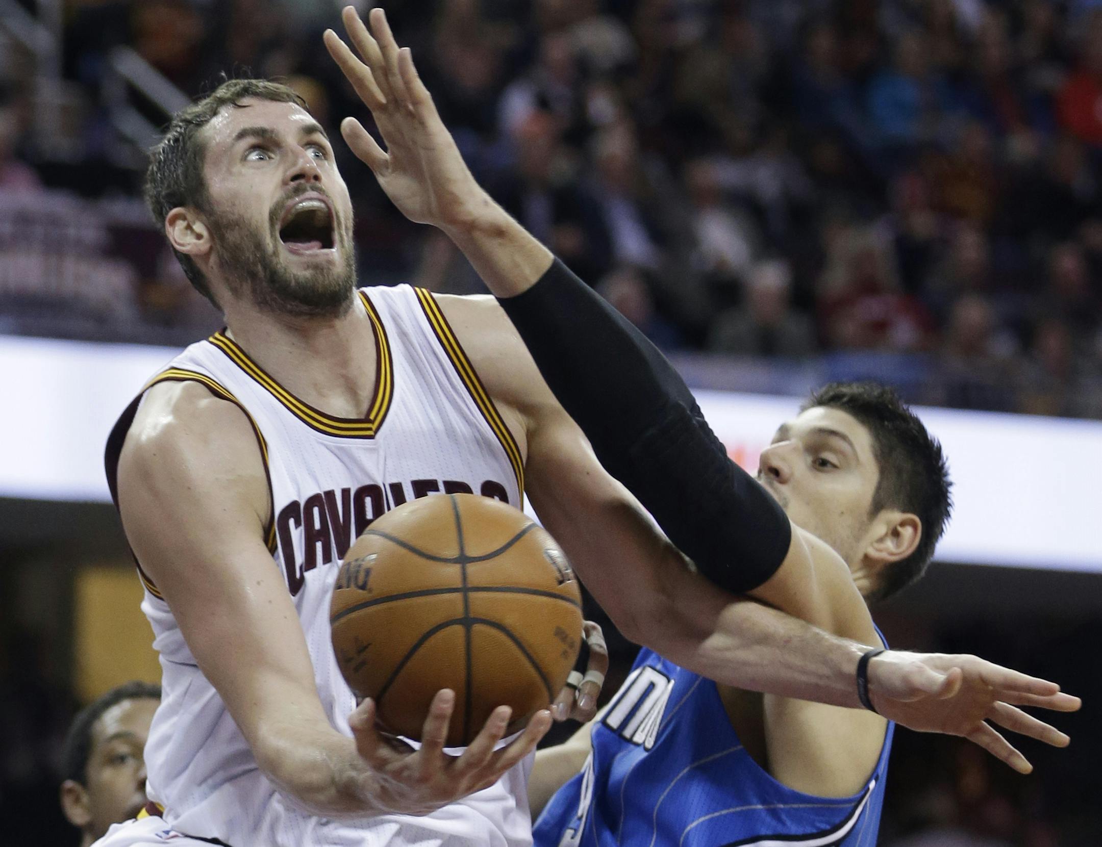 Cleveland Cavaliers' Kevin Love, left, drives past Orlando Magic's Nikola Vucevic (9), from Montenegro, during the second quarter of an NBA basketball game Monday, Nov. 24, 2014, in Cleveland. (AP Photo/Tony Dejak) ORG XMIT: OHTD102