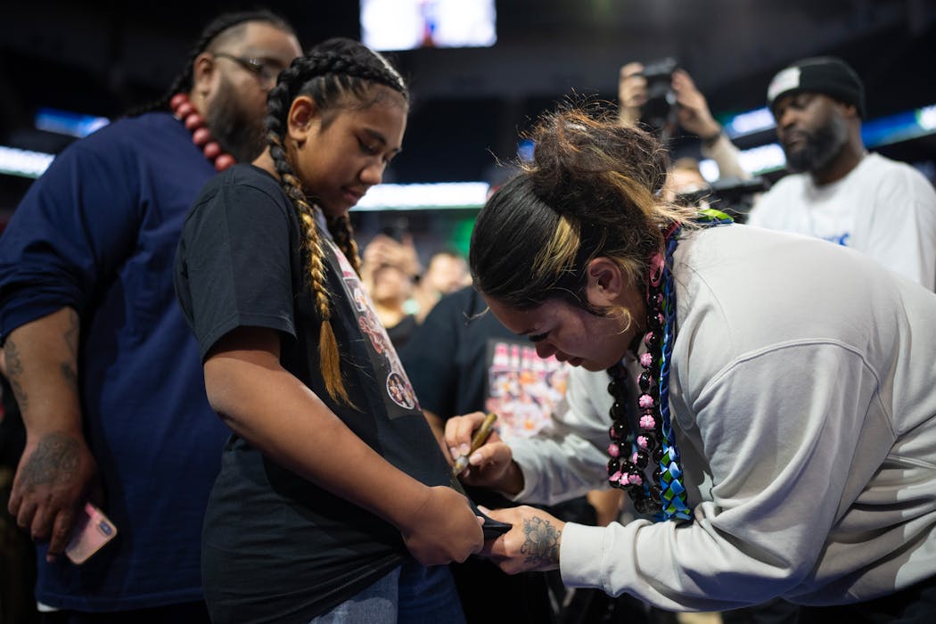 Alissa Pili signs a T-shirt worn by Angileena Moimoi, 11, a member of the local Samoan community and basketball player. 
