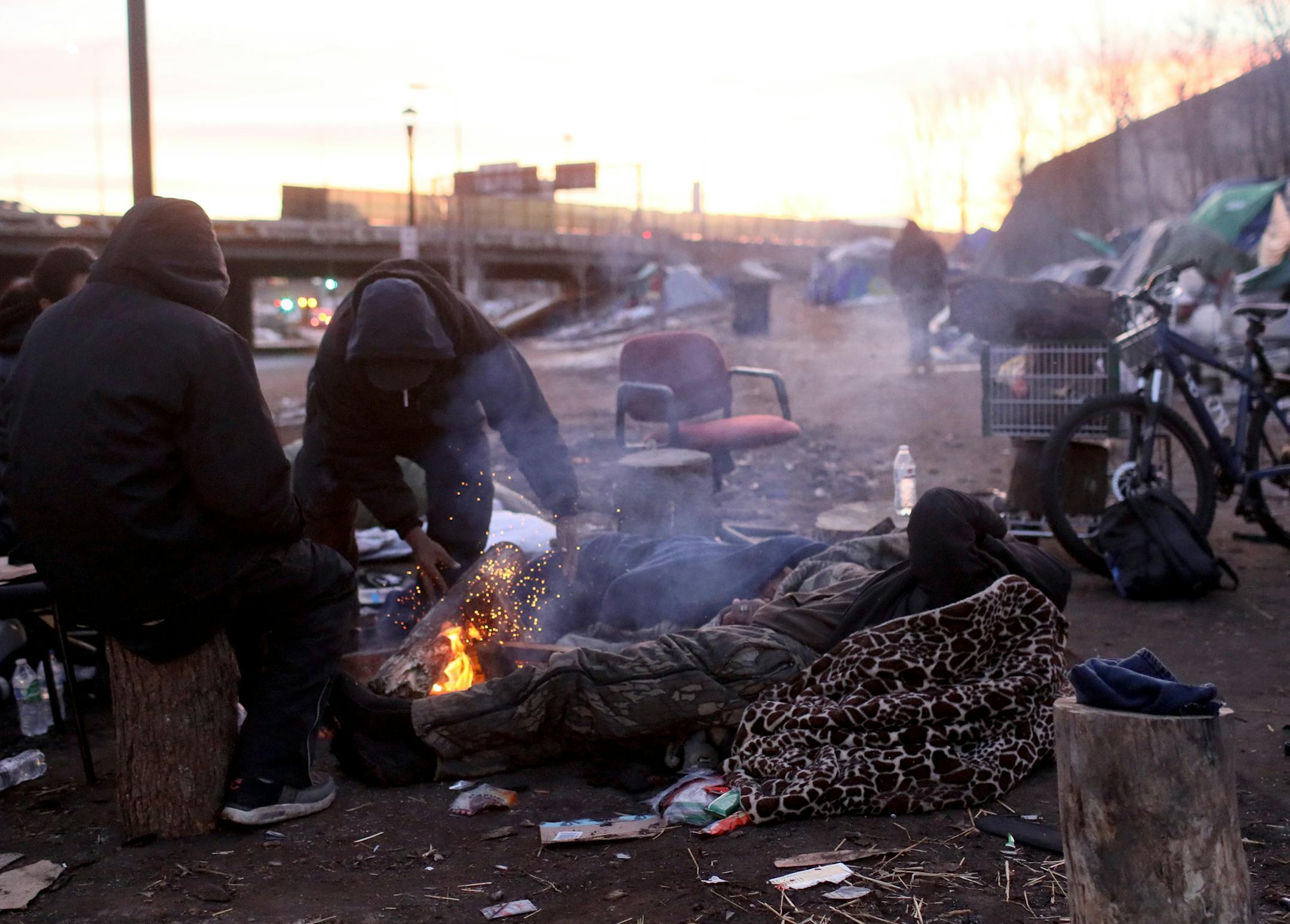 The number of residents is dwindling at the Hiawatha Homeless encampment as many have moved to the new navigation center Tuesday, Dec. 18, 2018, in Minneapolis, MN. Here, in what may have been the last camp fire to burn at the encampment residents warm themselves along Franklin Ave.] DAVID JOLES &#x2022; david.joles@startribune.com Encampment followup
