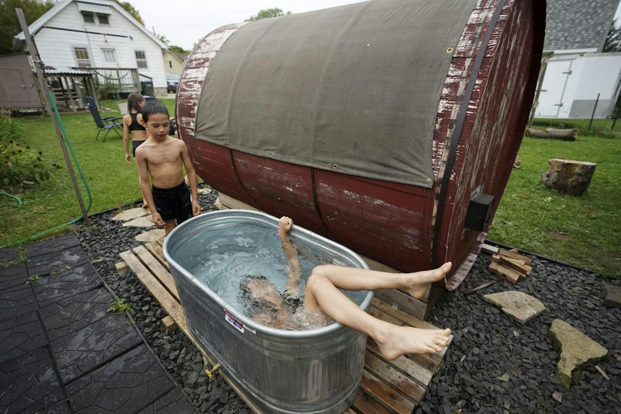 Becca Rice, 12, takes a dip in the cool down tub as 8-year-old Hudson waits his turn after a round in the barrel sauna.