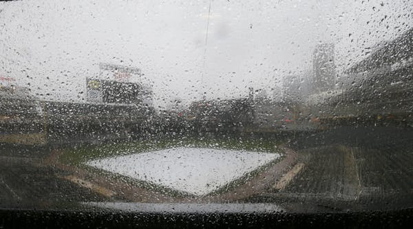 Rain falls on the tarp-covered field as the Minnesota Twins baseball game against the Detroit Tigers in Minneapolis, Sunday, April 27, 2014, is postpo