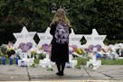 FILE - In this Monday, Oct. 29, 2018 file photo, a person stands in front of Stars of David that are displayed in front of the Tree of Life Synagogue 