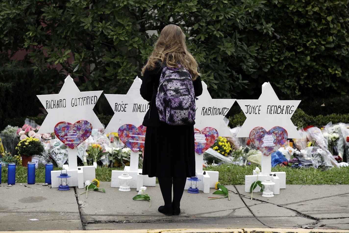 FILE - In this Monday, Oct. 29, 2018 file photo, a person stands in front of Stars of David that are displayed in front of the Tree of Life Synagogue with the names of those killed in Saturday's deadly shooting in Pittsburgh. A Jewish civil rights group says at least a dozen white supremacists have been arrested on allegations of plotting, threatening or carrying out anti-Semitic attacks in the U.S. since the massacre at the Pittsburgh synagogue in 2018. (AP Photo/Matt Rourke, File)