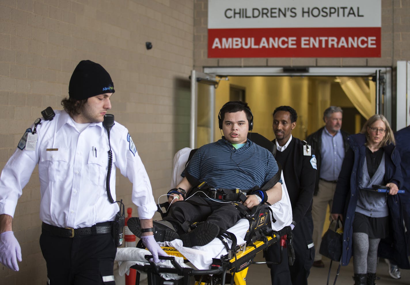 Matt Johnson, strapped to a gurney, is transported to an ambulance by Alina Health EMTs Ryan Duff, left, and Din Mohamoud, center, to travel from United Hospital in St. Paul to his new group home. ] (Leila Navidi/Star Tribune) leila.navidi@startribune.com BACKGROUND INFORMATION: Monday, April 4, 2016 at United Hospital in St. Paul. Matt Johnson, 19, who has severe mental and developmental disabilities, was brought to United Hospital's emergency room after he attacked someone at his group home. H