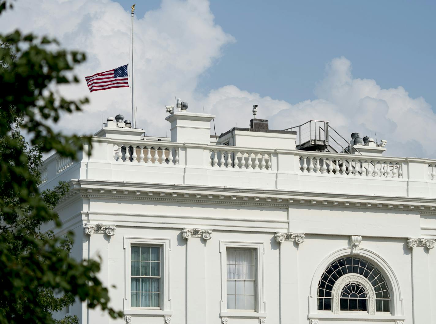 The American flag files at half-staff at the White House, Monday afternoon, Aug. 27, 2018, in Washington. Two days after Sen. John McCain's death, President Donald Trump says he respects the senator's "service to our country" and has signed a proclamation to fly the U.S. flag at half-staff until his burial. The flag atop the White House flew at half-staff over the weekend but was raised Monday and then lowered again amid criticism. (AP Photo/Andrew Harnik)