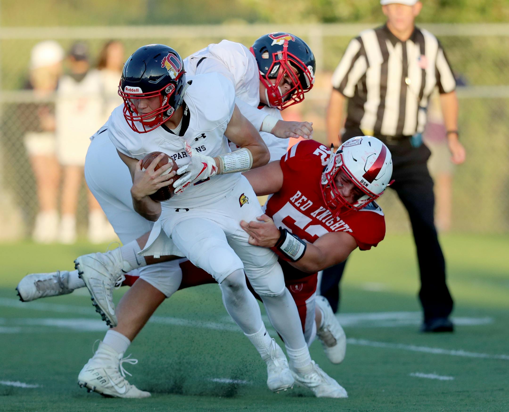 Benilde-St. Margaret's defender Nick Marinaro (52) grasps Orono quarterback Teddy Deters while being blocked during the first half Friday, Aug. 30, 2019, at Benilde-St. Margaret's High School in St. Louis Park, MN. Orono was called for holding on the play.] DAVID JOLES • david.joles@startribune.com Orono at Benilde-St. Margaret's prep football
