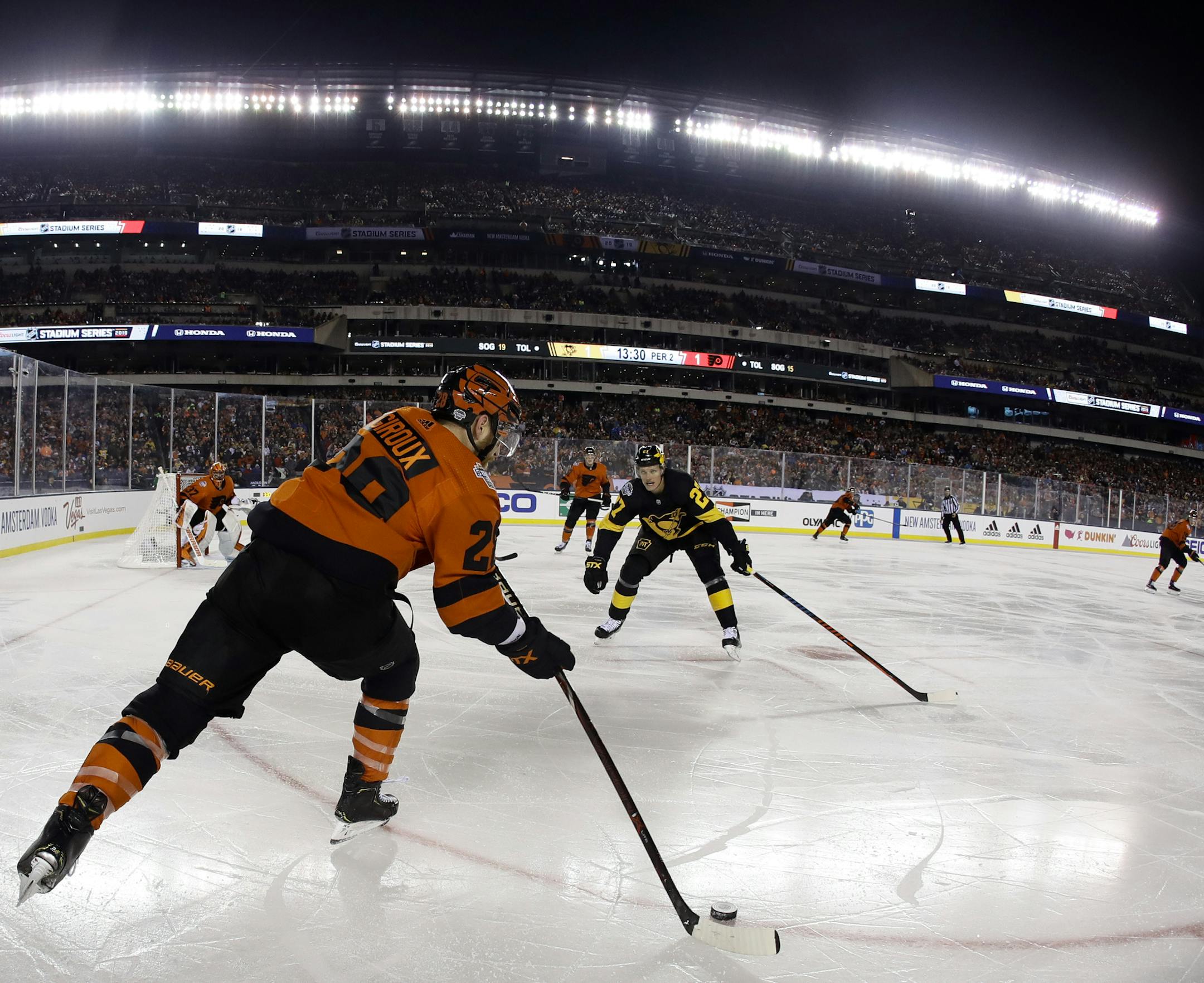 Philadelphia Flyers' Claude Giroux (28) passes the puck as Pittsburgh Penguins' Nick Bjugstad (27) defends during the second period of an NHL Stadium Series hockey game at Lincoln Financial Field, Saturday, Feb. 23, 2019, in Philadelphia. (AP Photo/Matt Slocum)