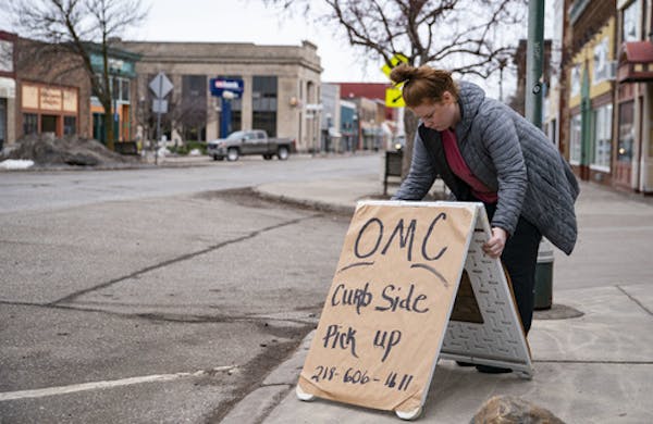 Emma Hirsch place the sign for OMC Smokehouse's curb side pickup on the curb in front of the restaurant on Wednesday morning. ]
ALEX KORMANN &#x2022; 