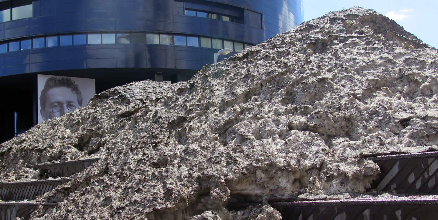 Snowbank - a small mountain of dirty snow slowly melts in the spring weather, -located on the plaza steps between the Guthrie theater and Mill Ruins Park . ] Tuesday, 4/08/2014, Minneapolis, MN