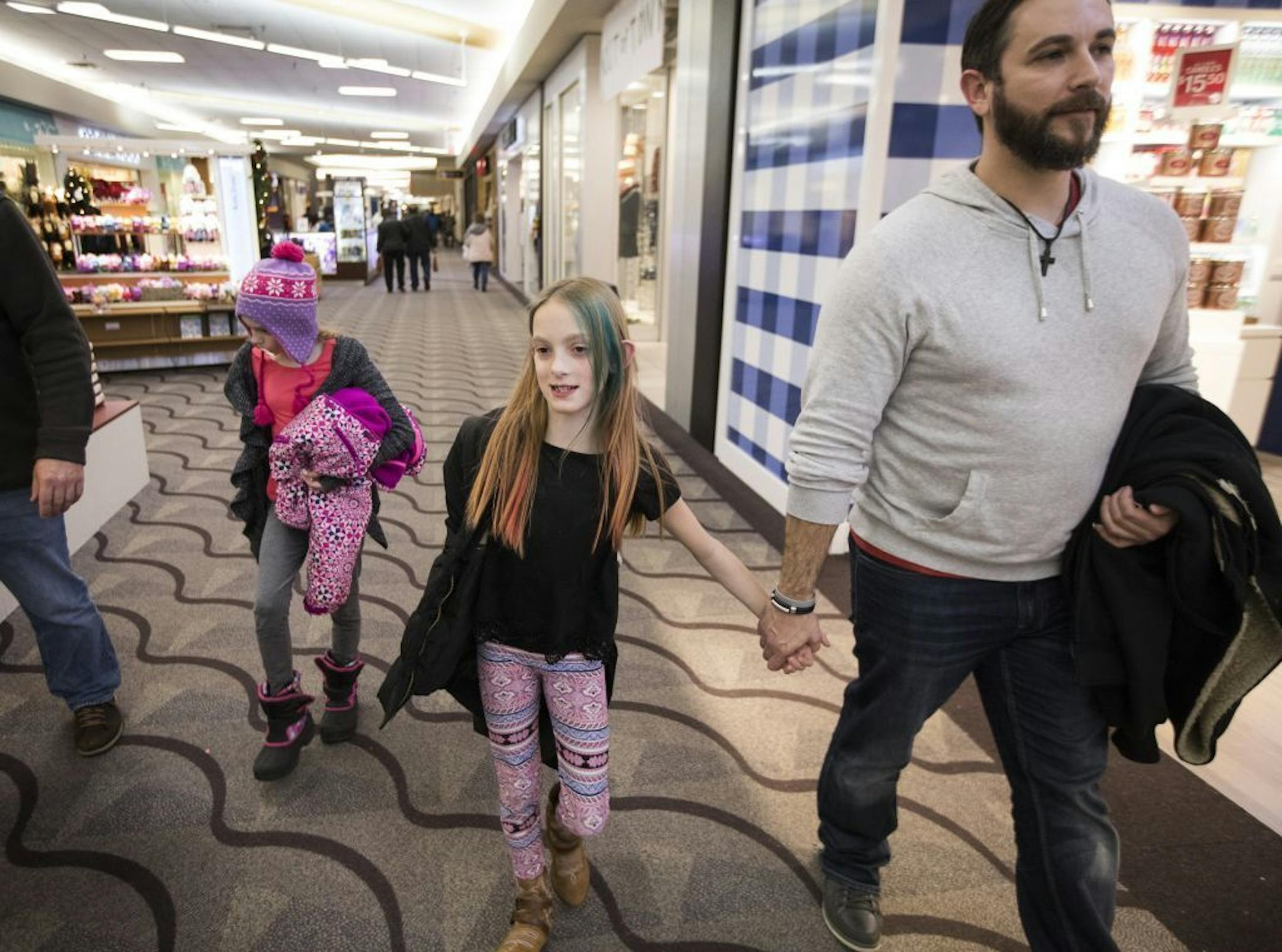 Abby Carlsen holds the hand of her dad, Jesse, on a trip to Kirkland Mall in Bismarck, N.D. Twin Isabelle is at left.