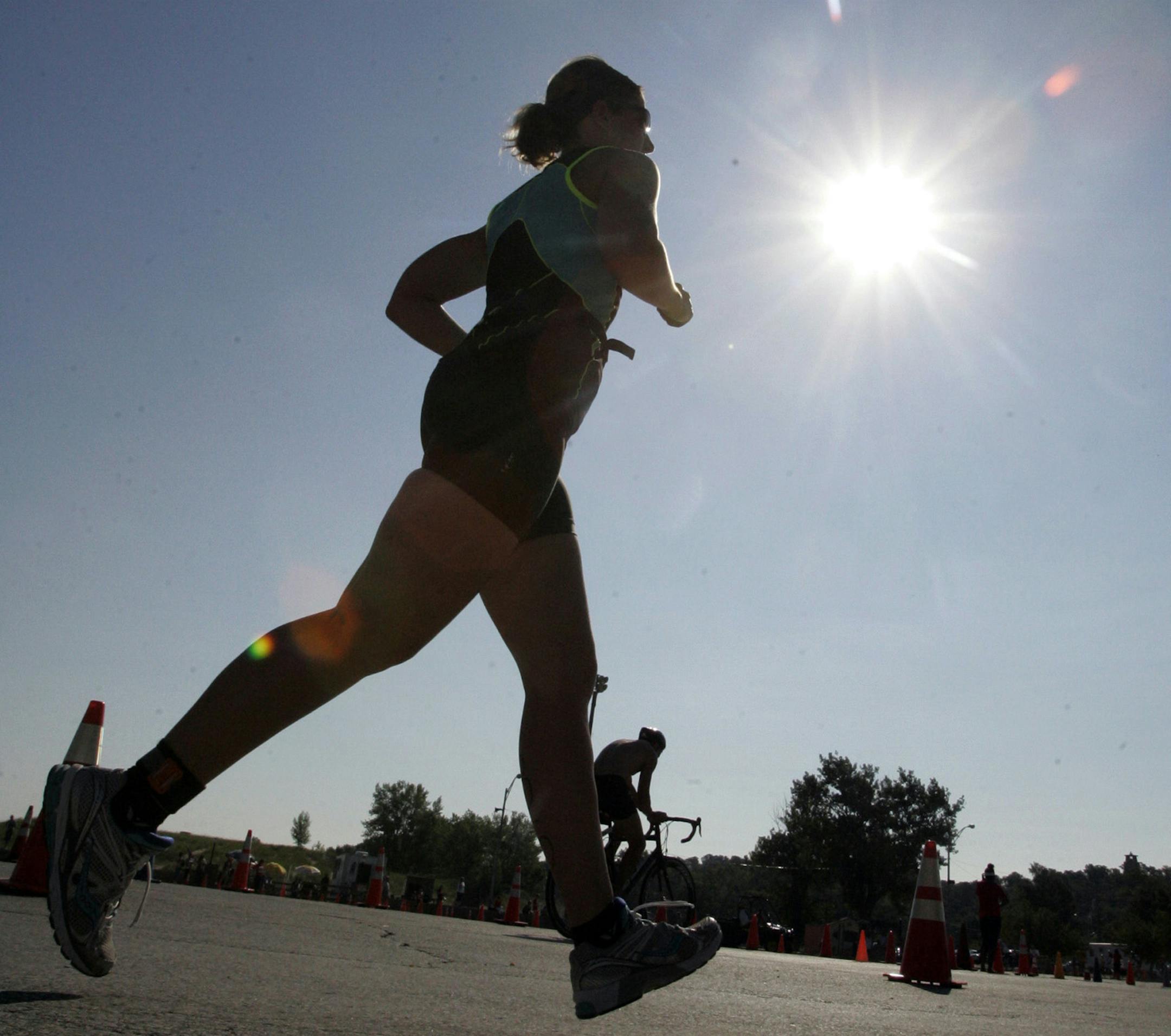The sun shines above an athlete as she starts the running leg of the Michigan City Triathlon in Washington Park Saturday, Aug. 10, 2013 in Michigan City, Ind. (AP Photo/The LaPorte Herald-Argus, Bob Wellinski)