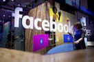 FILE - In this Tuesday, April 18, 2017, file photo, a conference worker passes a demo booth at Facebook's annual F8 developer conference in San Jose, 