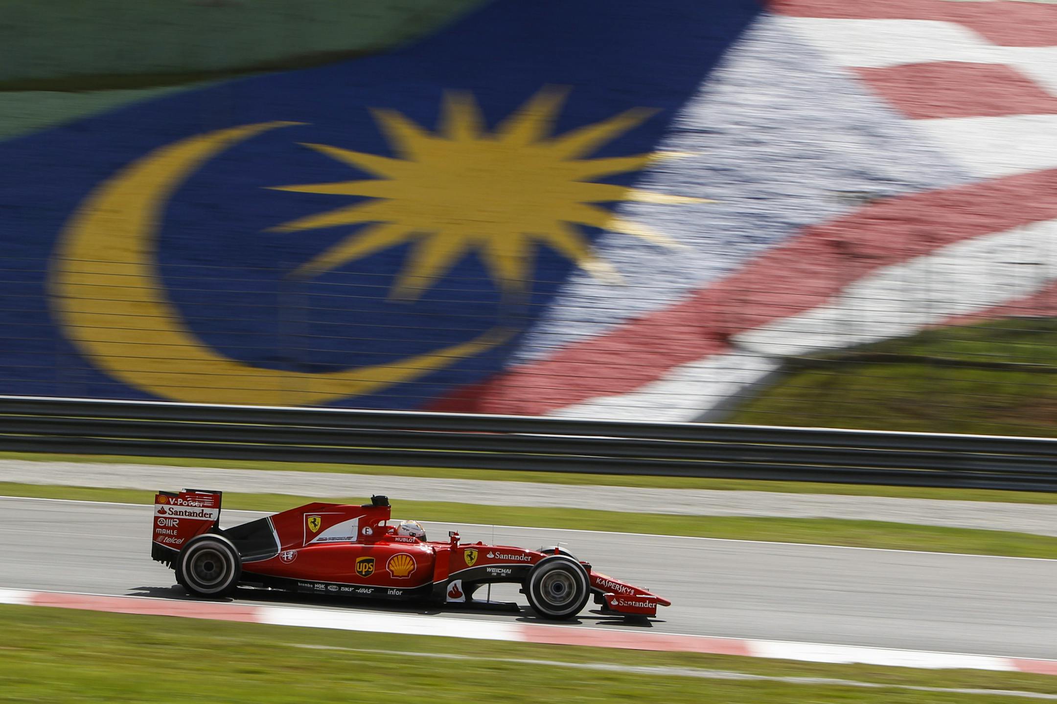 Ferrari driver Sebastian Vettel of Germany steers his car past a Malaysian flag decoration on his way to winning the Malaysian Formula One Grand Prix at Sepang International Circuit in Sepang, Malaysia, Sunday, March 29, 2015. (AP Photo/Joshua Paul)