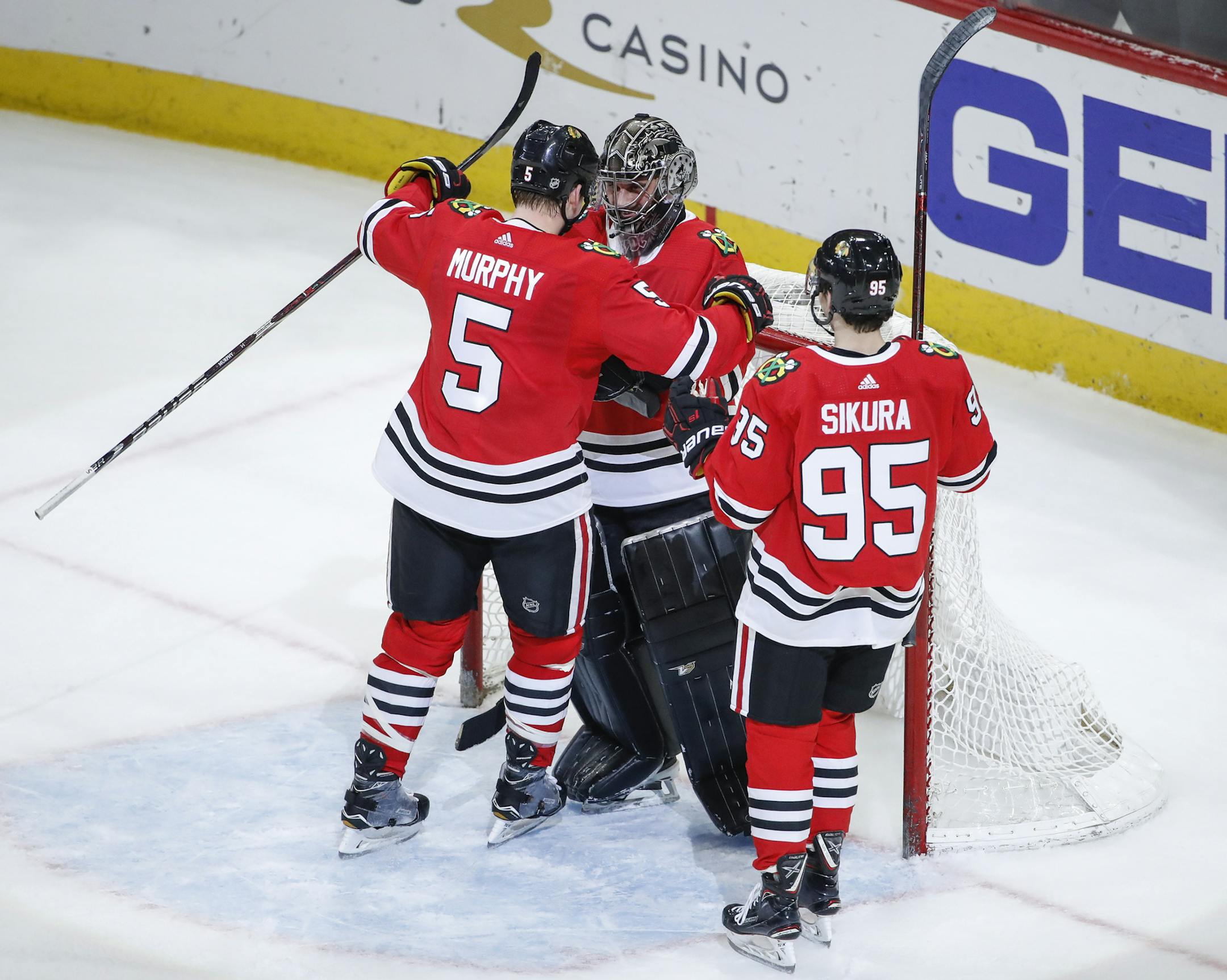 Chicago Blackhawks goalie Scott Foster (90) celebrates with defenseman Connor Murphy (5) and right wing Dylan Sikura (95) after defeating the Winnipeg Jets after an NHL hockey game Thursday, March 29, 2018, in Chicago. (AP Photo/Kamil Krzaczynski)