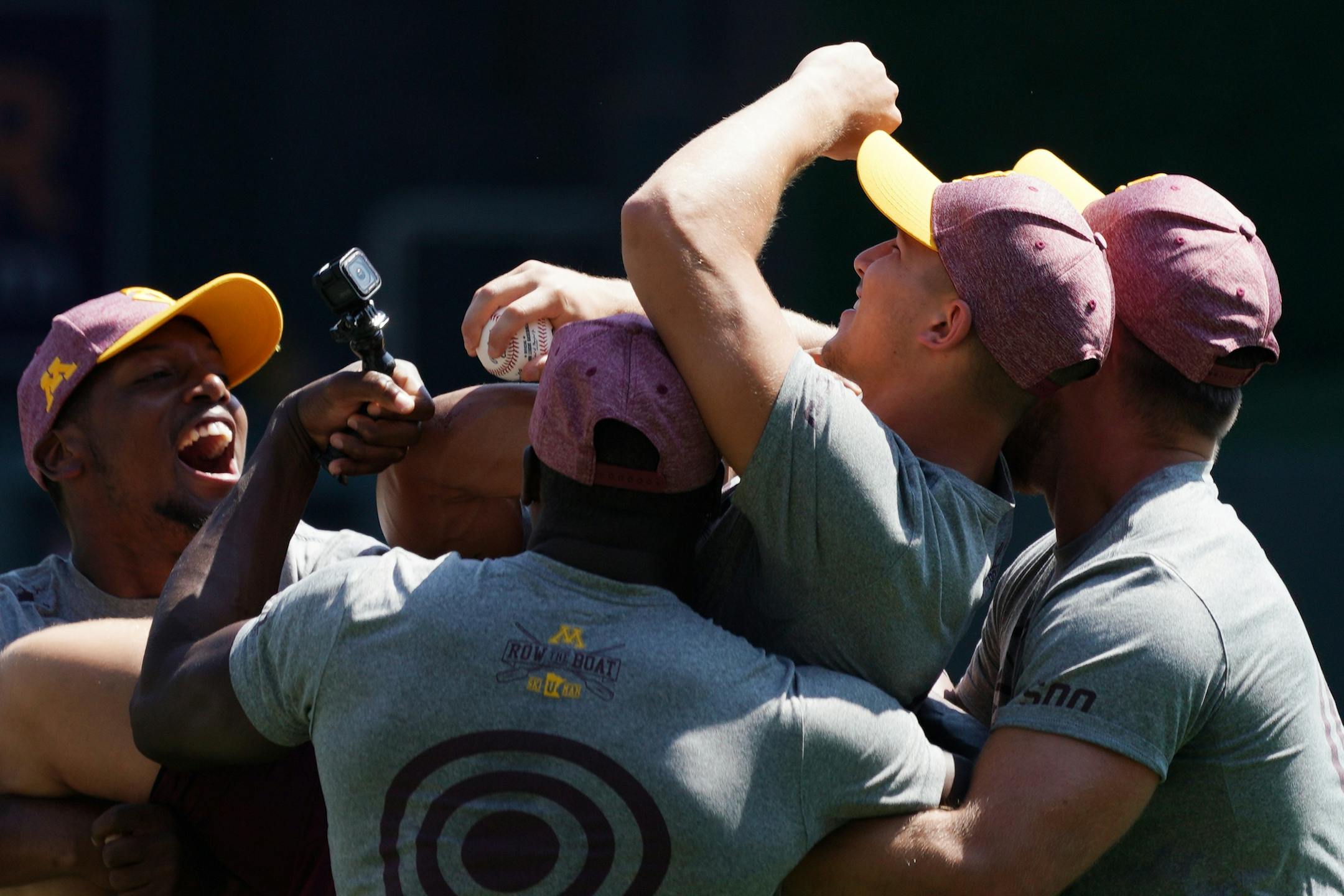 Gophers wide receiver Clay Geary (18) was mobbed by his teammates as he found out he is a scholarship recipient after throwing out a ceremonial first pitch ahead of Wednesday's Twins game.