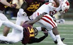 Wisconsin running back Dare Ogunbowale, right, tries to break free of Minnesota defensive back Eric Murray (31) in the first half of an NCAA college f