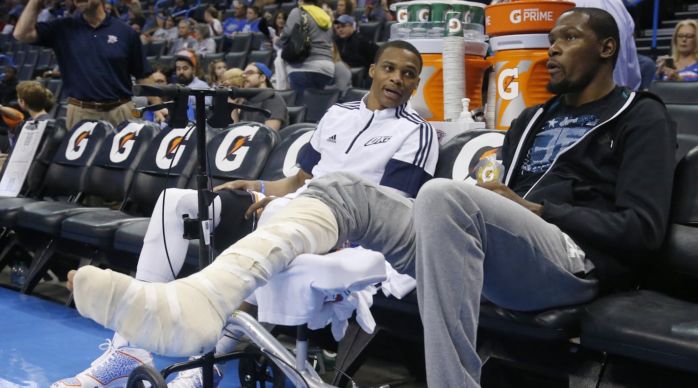 Oklahoma City Thunder guard Russell Westbrook, left, talks with teammate Kevin Durant before the Thunder's preseason NBA basketball game against the Utah Jazz in Oklahoma City, Tuesday, Oct. 21, 2014. (AP Photo/Sue Ogrocki)