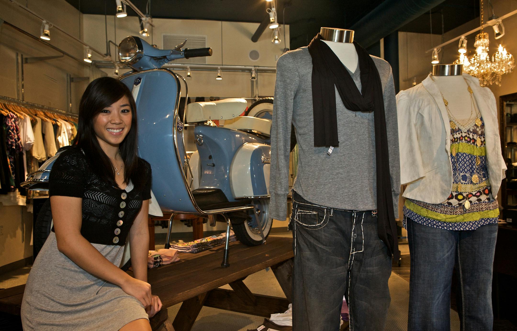 Thao Bui, owner of Parc Boutique, poses with some of the women's and men's clothing she sells in her shop. Her business partner imported the motor scooter behind her from Italy.