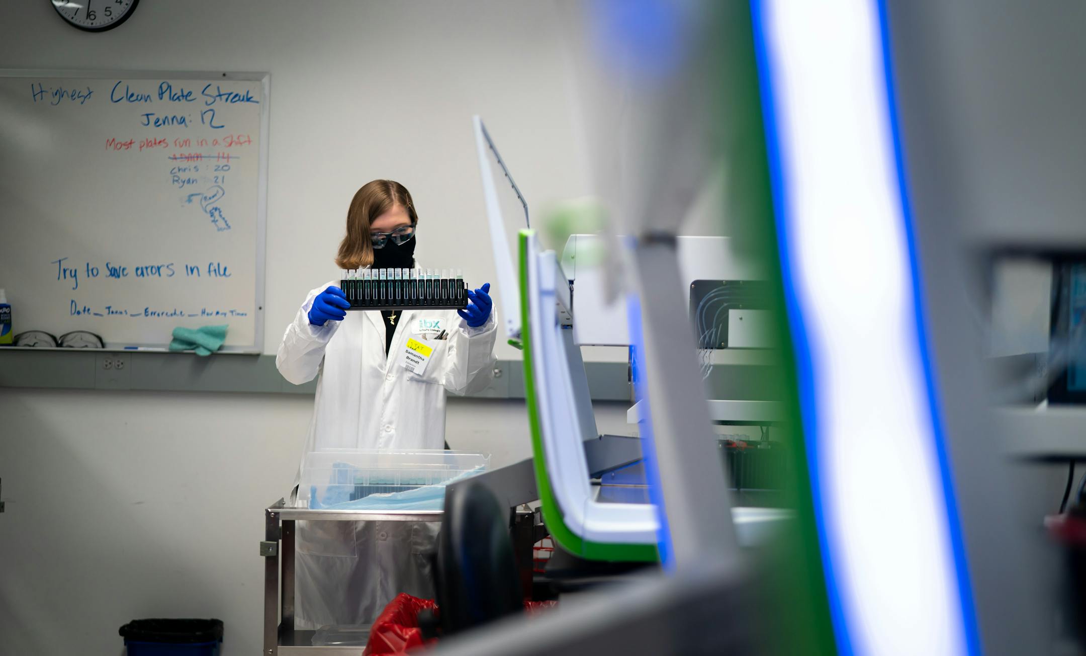 Samantha Brandt uncapped saliva samples, checked the volume for each sample, and prepared them for extraction. IBX, Infinity Biologix, has the ability to process up to 30,000 samples per day in this Oakdale, Minnesota facility. Saliva samples are neutralized by the blue activator in the tube, rendering the sample not contagious.