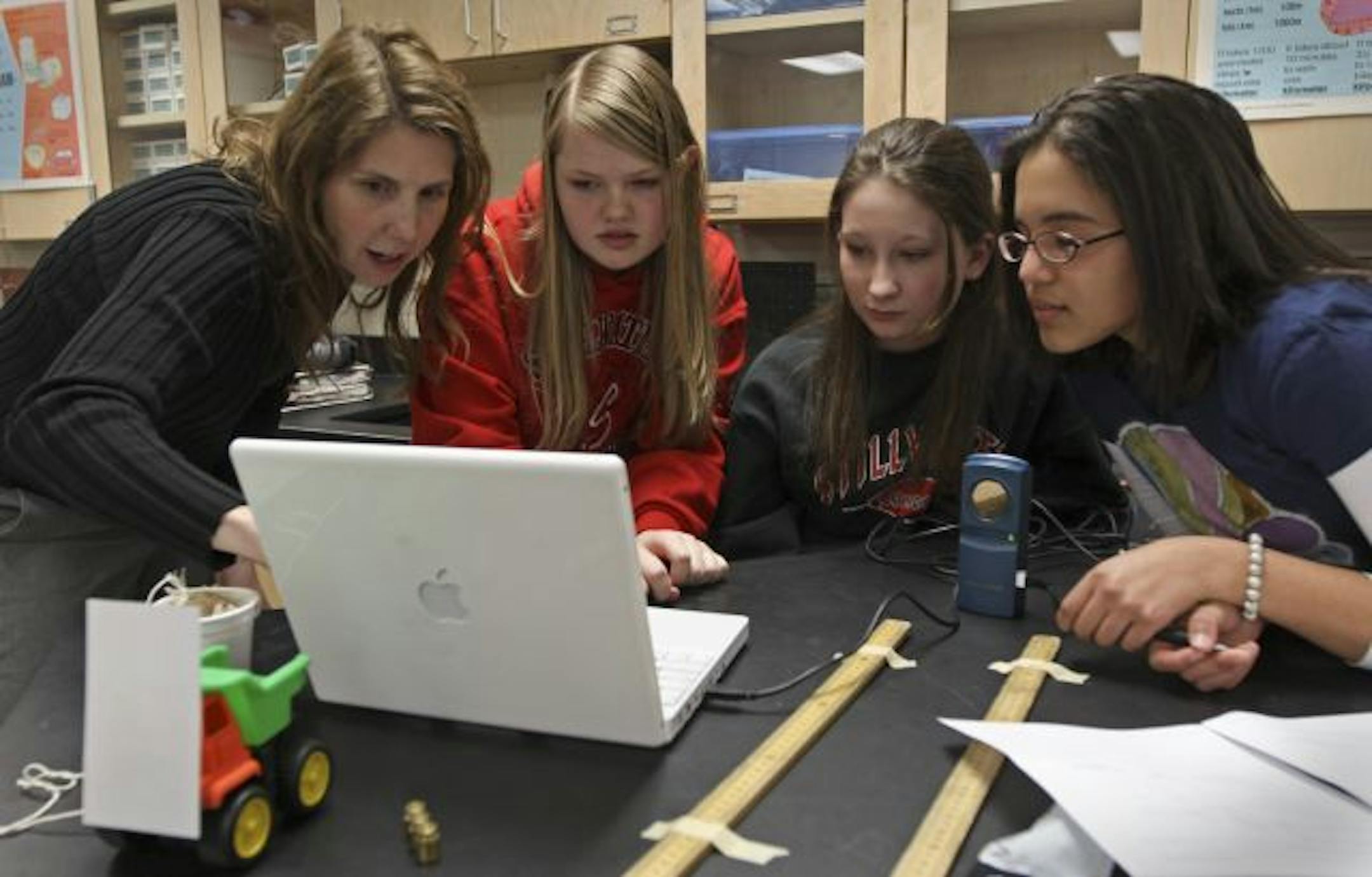 Every student at Oak-Land Junior High School in Lake Elmo gets a laptop to use in class and take home at night. Here teacher Katy Pupungatoa, left, helped ninth-graders Victoria Amundson, Meghan Jacobson and Laura Ruiz connect a laptop to an acceleration sensor during a class on Newton's second law of motion.
