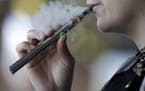 In this Friday, Oct. 4, 2019 file photo, a woman using an electronic cigarette exhales in Mayfield Heights, Ohio.