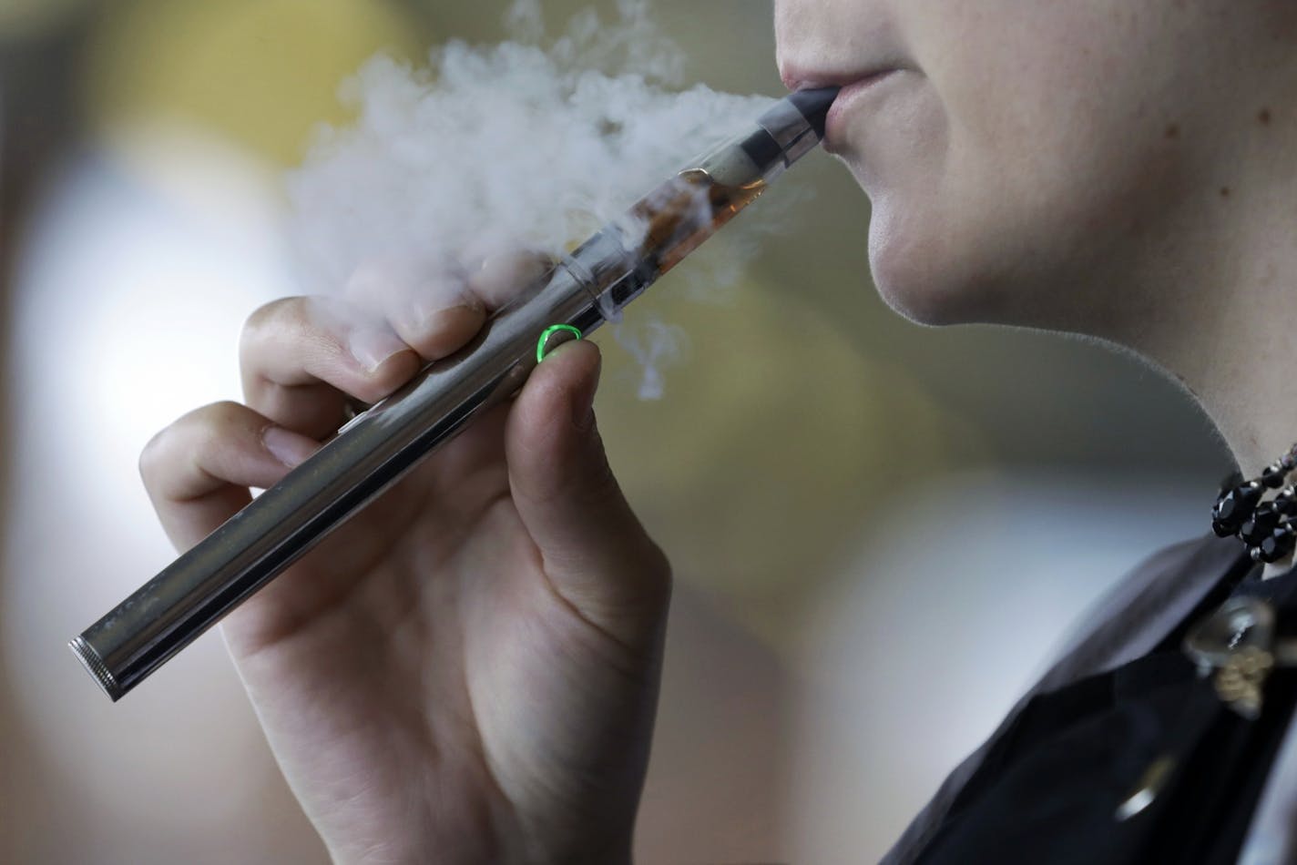 In this Friday, Oct. 4, 2019 file photo, a woman using an electronic cigarette exhales in Mayfield Heights, Ohio.