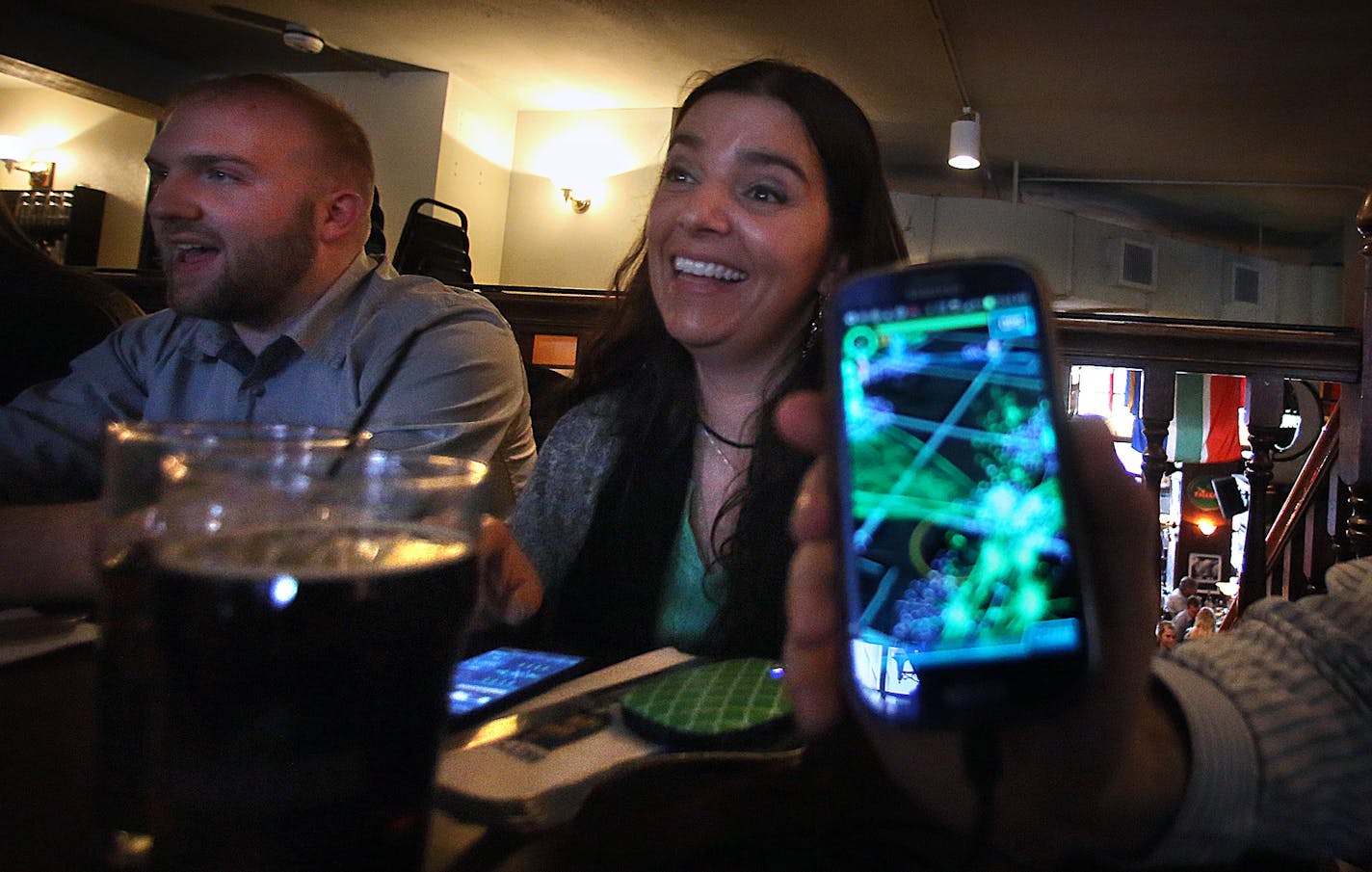 Fe Strait (middle), James Misuraca (left) and Jason Hager (holding phone) prepared to play Ingress while dining at a downtown restaurant. ] JIM GEHRZ &#x201a;&#xc4;&#xa2; jgehrz@startribune.com / Minneapolis, MN / March 28, 2014 / 6:00 PM / BACKGROUND INFORMATION: A group of people who play Ingress, an augmented reality game, met recently in Minneapolis to play the game. Ingress is like a geocache, capture the flag-like game, played on smartphones. After visiting and enjoying a meal and drinks a